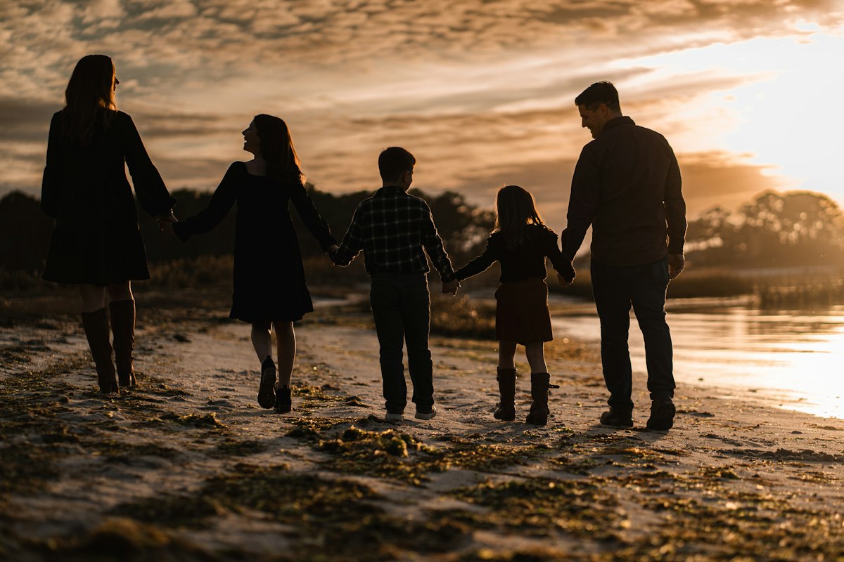 Famille marchant sur la plage au coucher du soleil, symbole de protection et de transmission patrimoniale